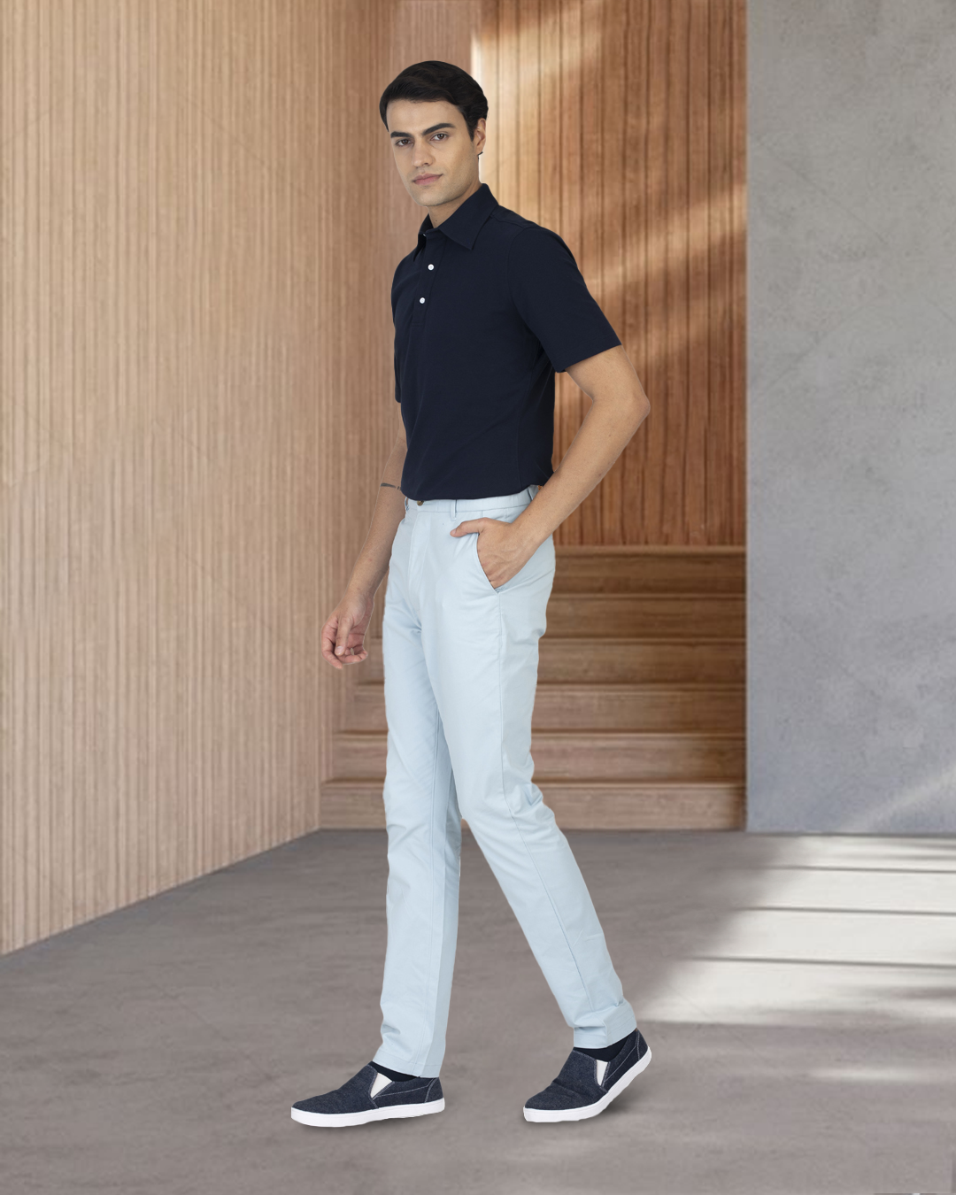 Model wearing the custom oxford polo shirt for men by Luxire in navy with white pants 3