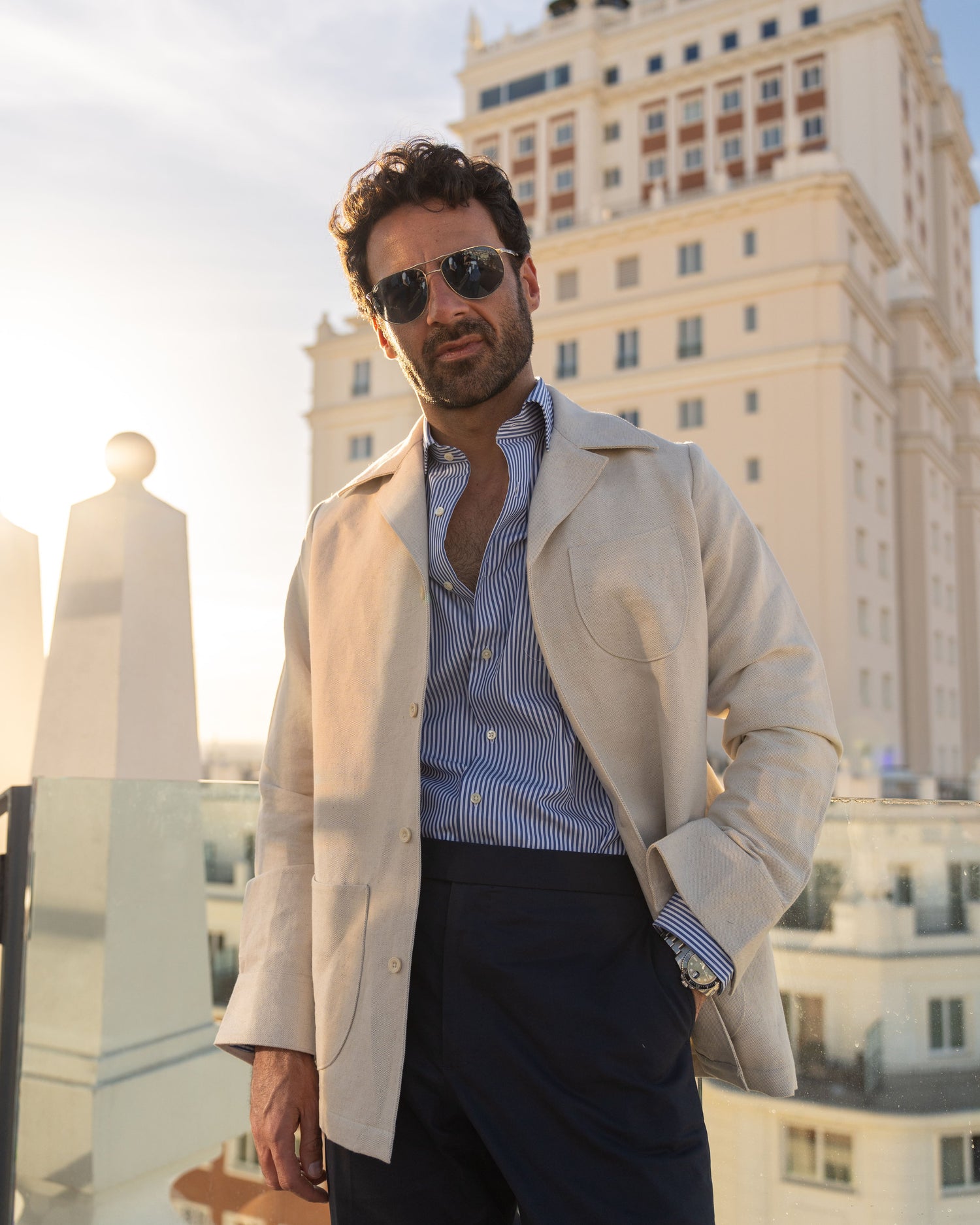 Model outside wearing the linen shirt jacket for men by Luxire in cream wearing sunglasses in front of building