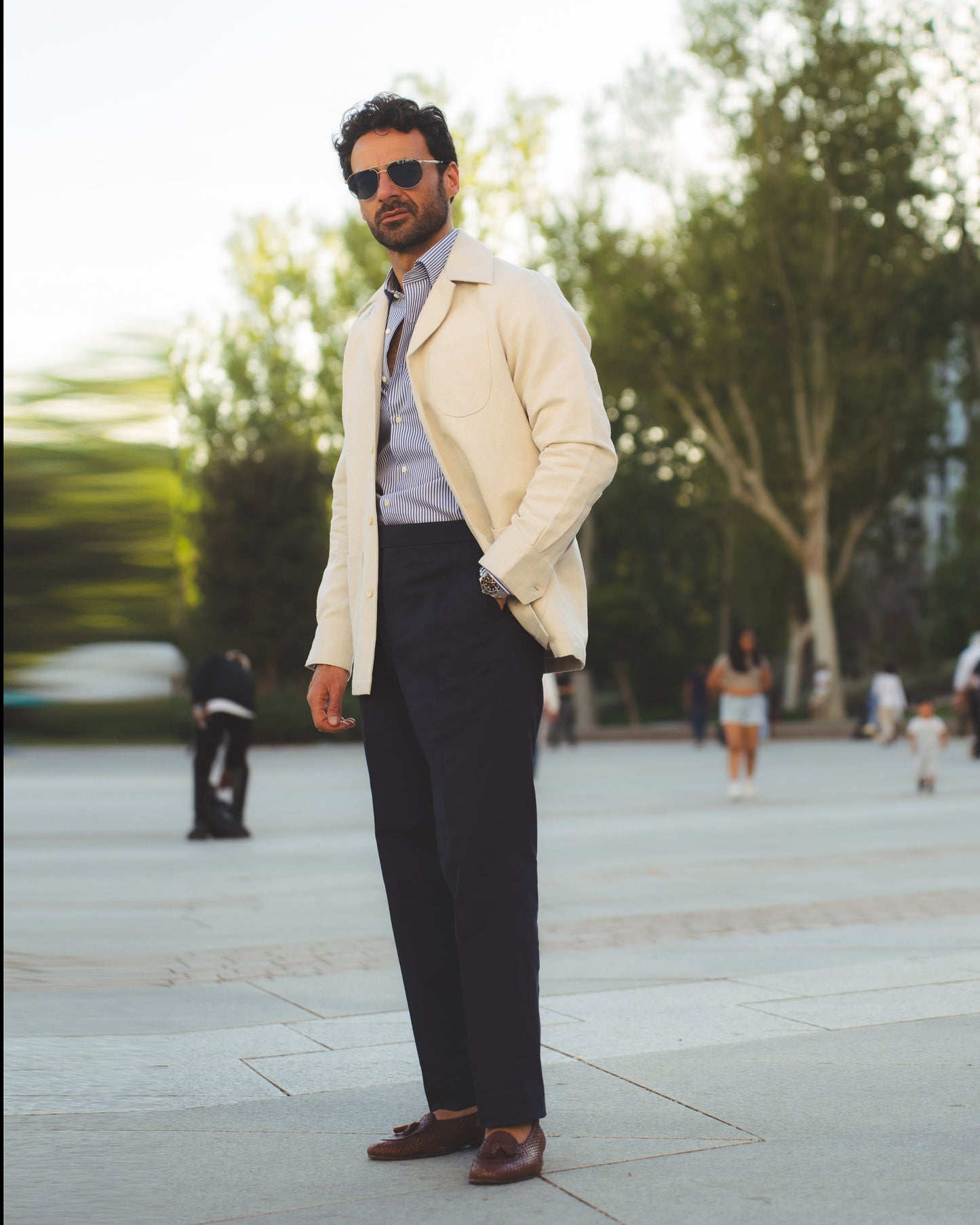 Model outside wearing the linen shirt jacket for men by Luxire in cream wearing sunglasses one hand in pocket 2