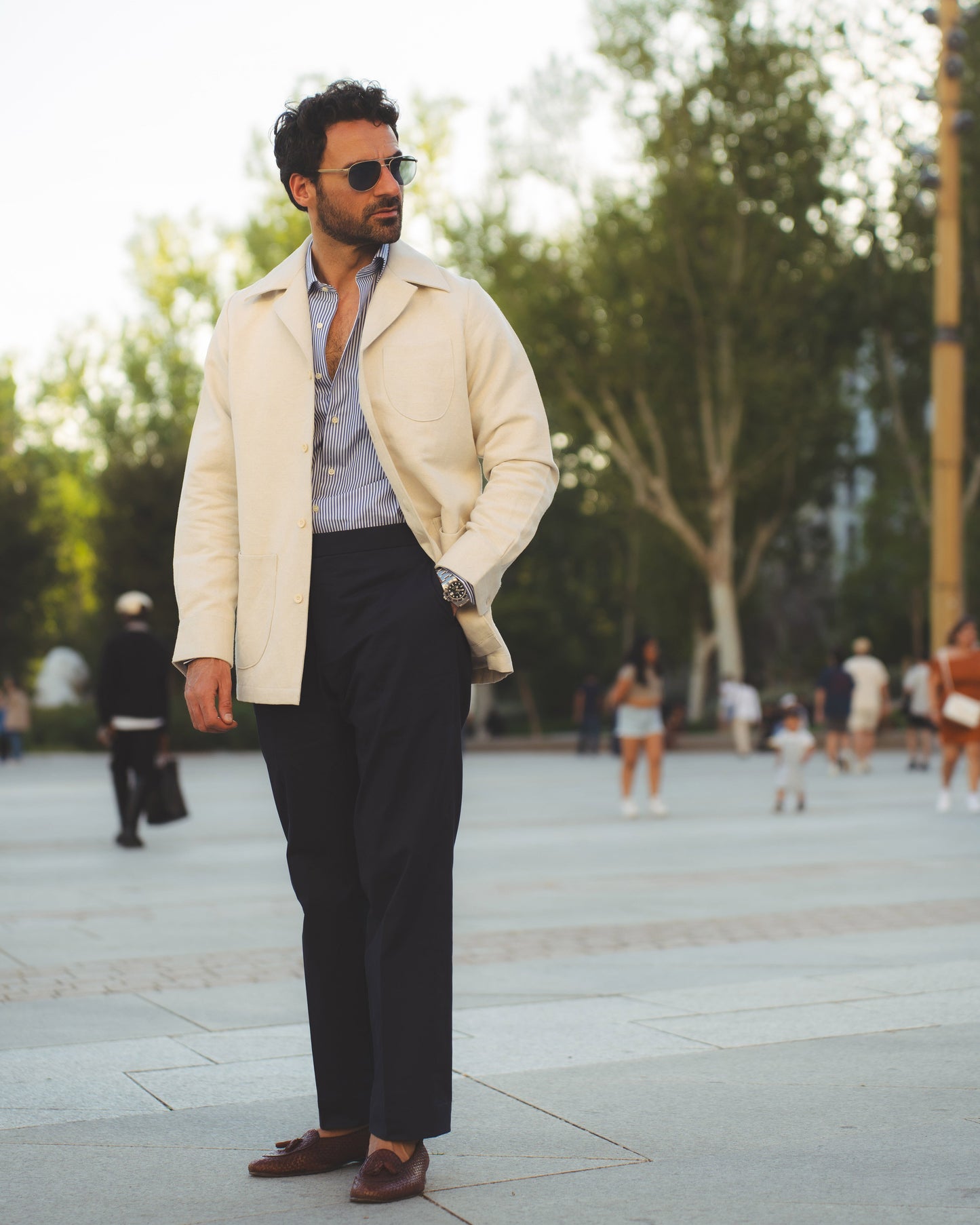 Model outside wearing the linen shirt jacket for men by Luxire in cream wearing sunglasses one hand in pocket 3