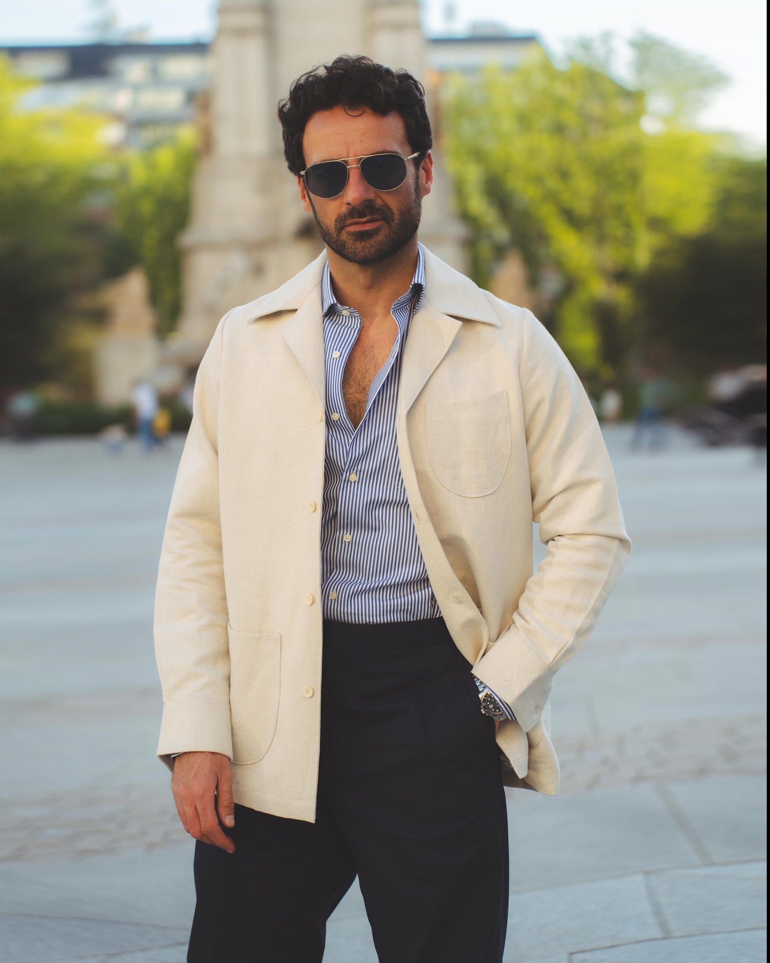 Model outside wearing the linen shirt jacket for men by Luxire in cream wearing sunglasses one hand in pocket 4