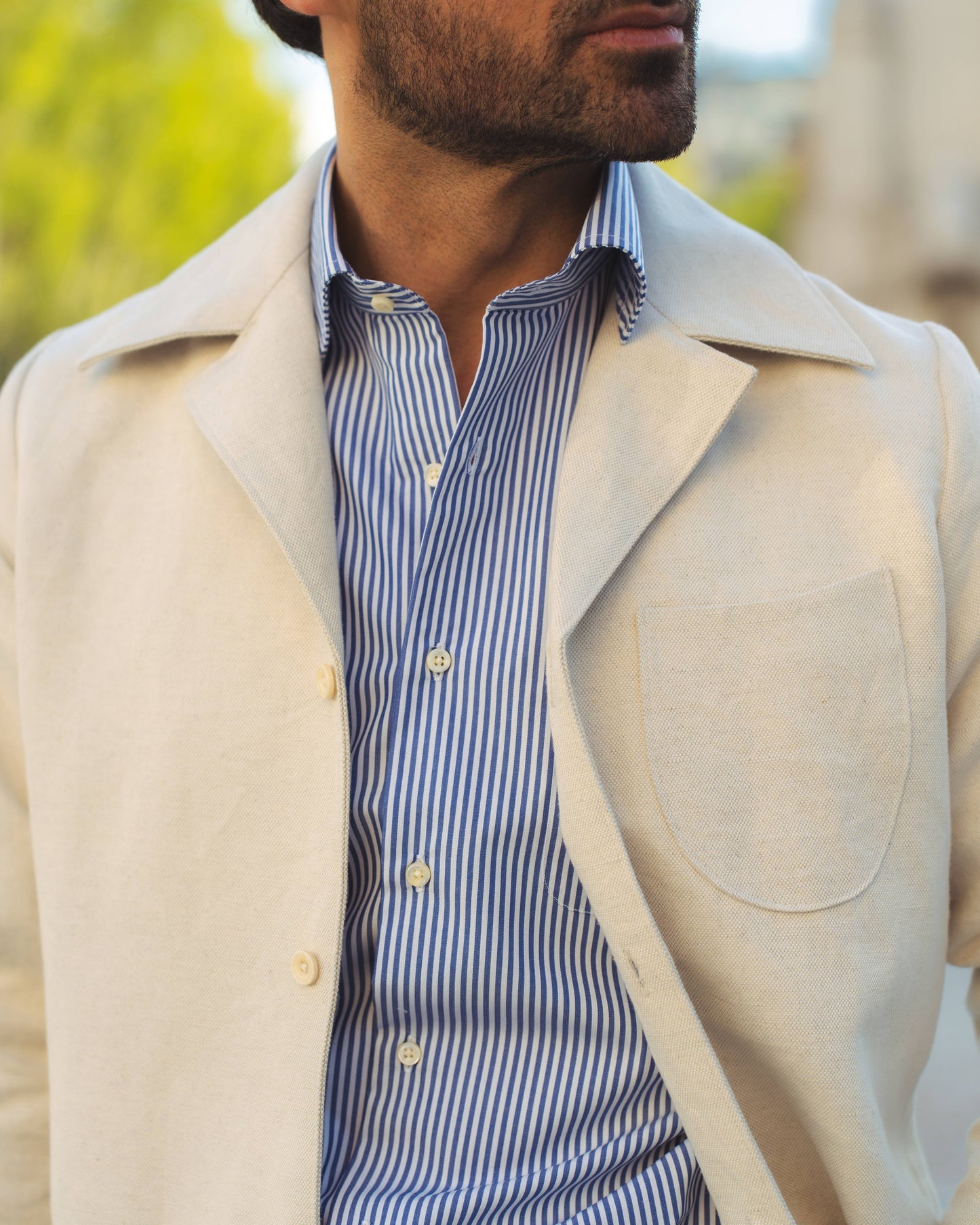 Model outside wearing the linen shirt jacket for men by Luxire in cream wearing striped shirt
