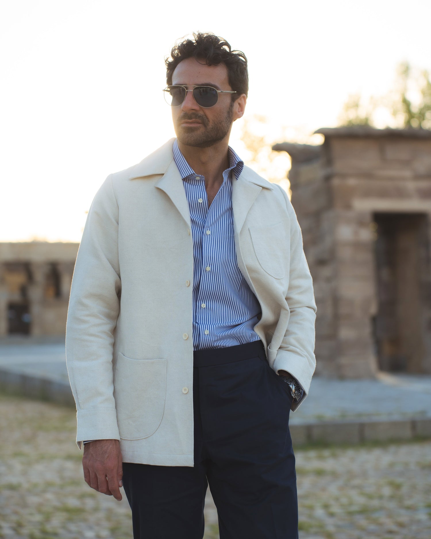 Model outside wearing the linen shirt jacket for men by Luxire in cream wearing sunglasses one hand in pocket